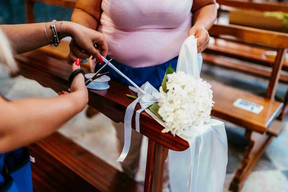Mani che rifiniscono un bouquet bianco con il nastro