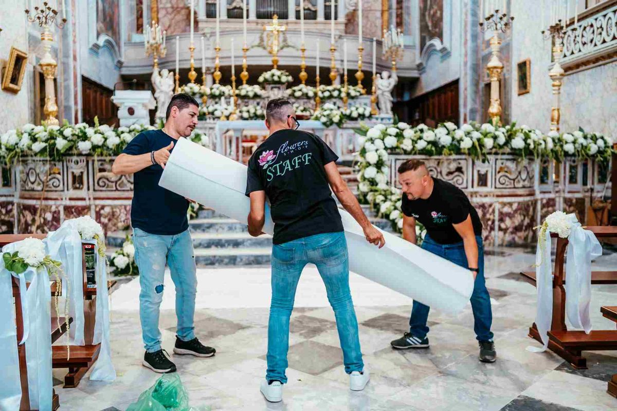 Tre persone della squadra Flowers Shop trasportano una struttura in chiesa