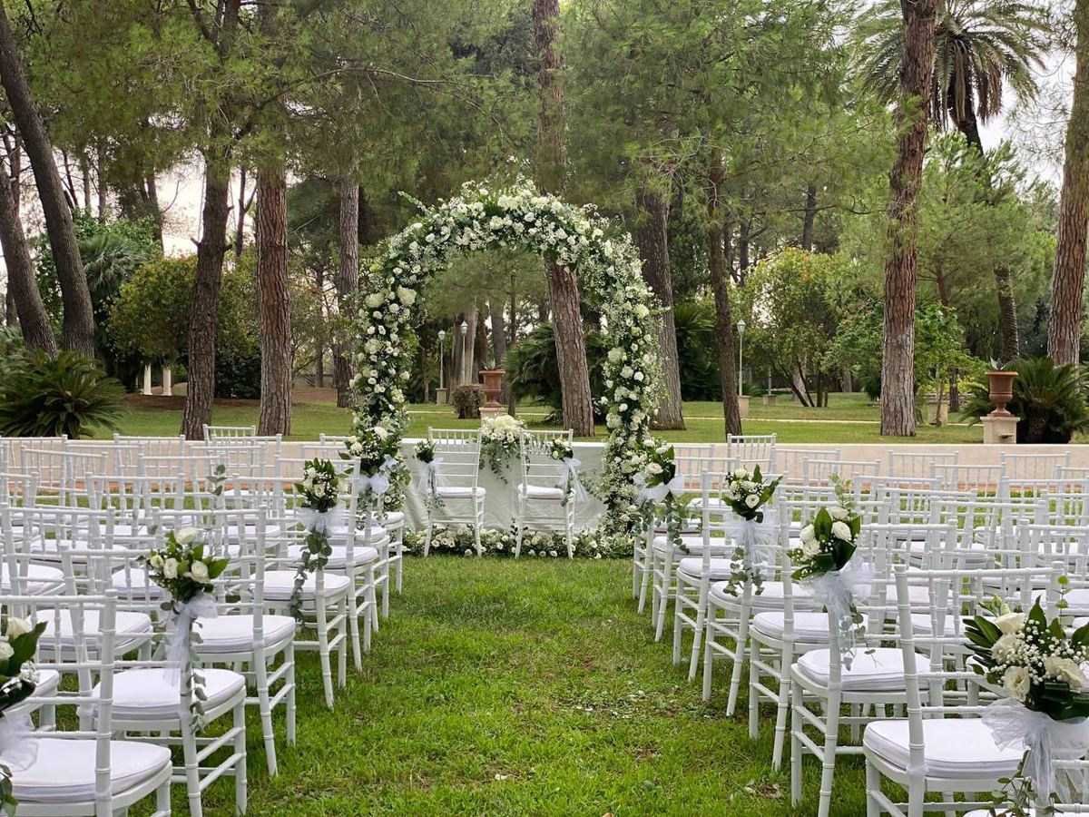 Arco fiorito e sedie bianche in un giardino
