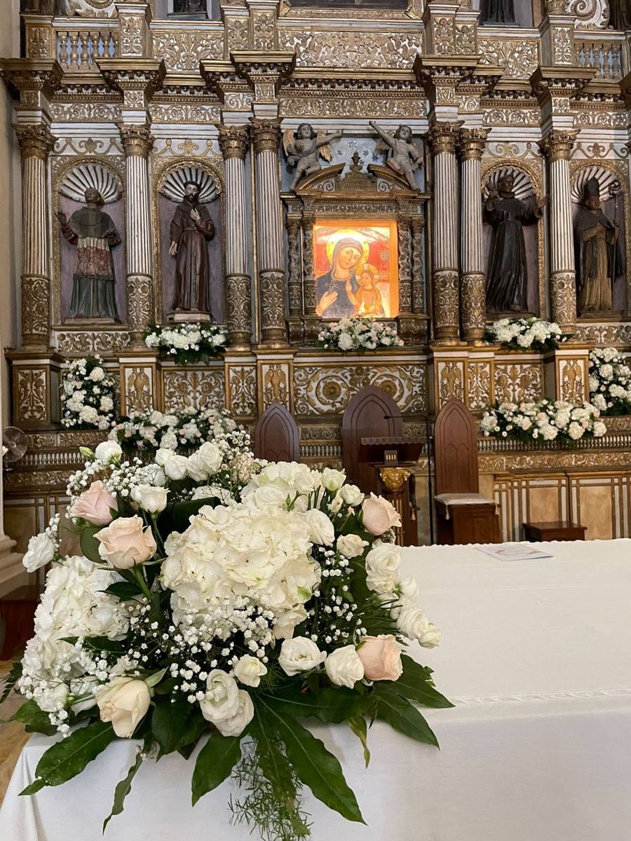 Composizione di fiori bianchi davanti a un altare barocco