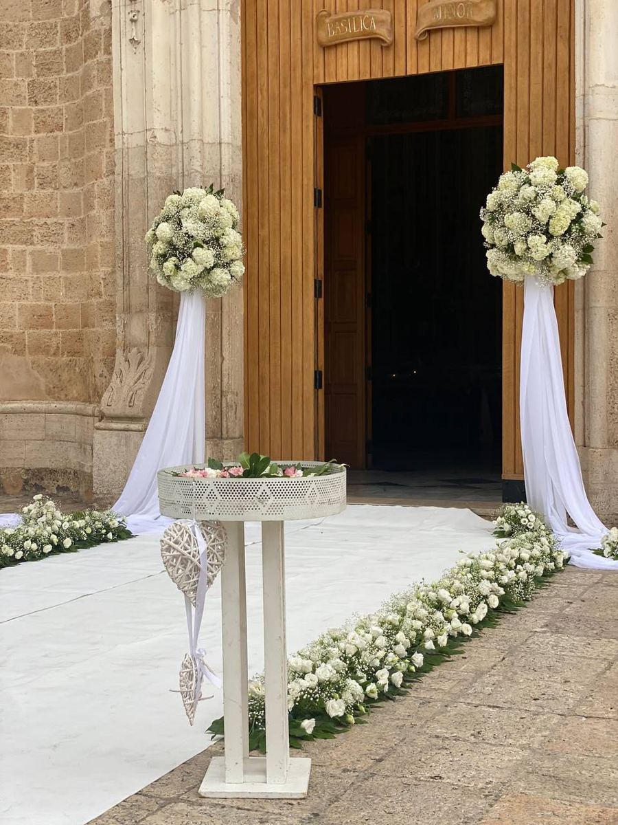 Ingresso di una chiesa con colonne fiorite e drappi bianchi